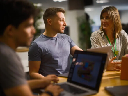 Several people gather at a desk