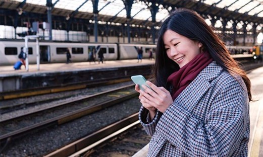 Female staring at mobile in a train station