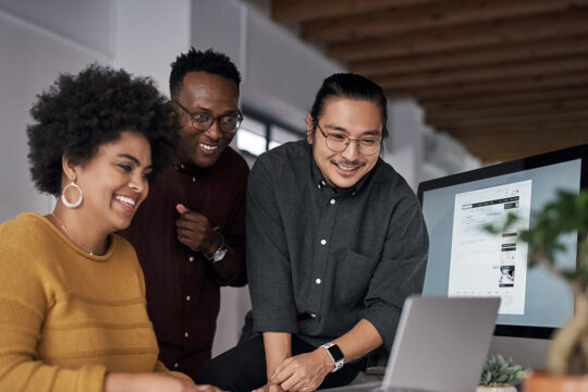 Three colleagues staring at a monitor